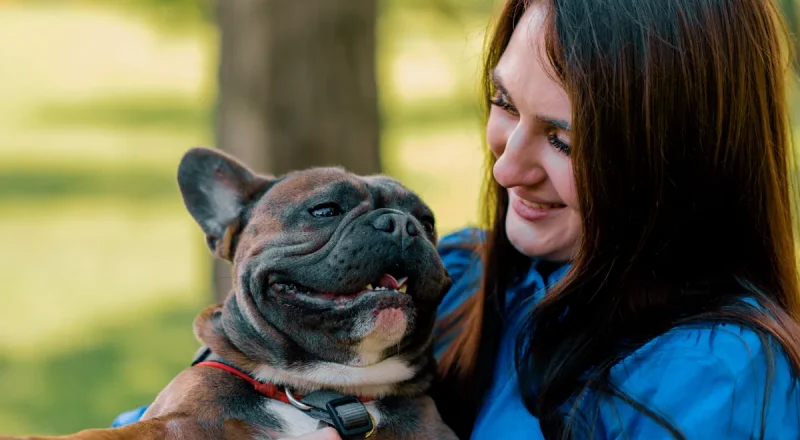 Une femme qui tient un bouledogue francais dans ses bras